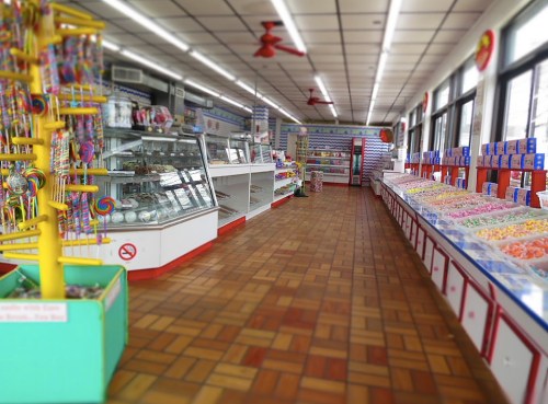 Brightly lit candy store interior with colorful displays of sweets, lollipops, and a glass case of treats.
