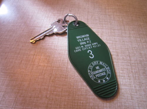 A green motel keychain with the number 3, labeled "Wigwam Village Inn #7, Cave City, KY." A key is attached.