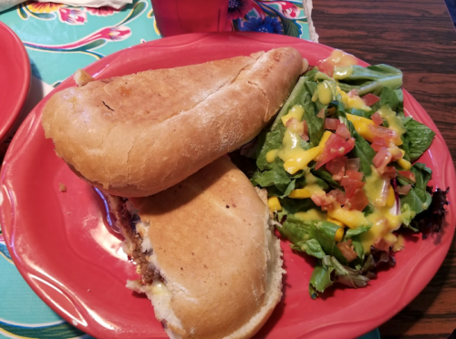 A plate with two toasted sandwiches and a side salad topped with cheese, tomatoes, and dressing.