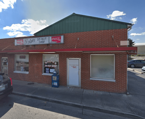 A brick building with a red awning, featuring a sign for "Ralph's Do-Nut Shop" and Coca-Cola branding.