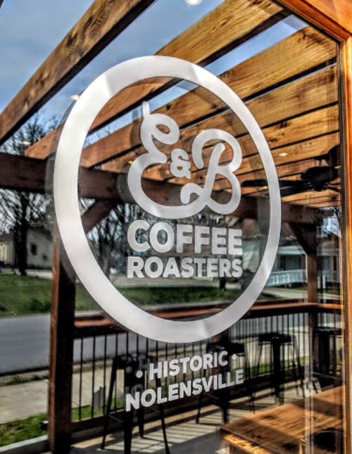 Logo of E&B Coffee Roasters displayed on a glass window, with a view of a street in Nolensville.