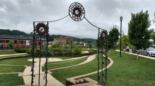 A decorative archway at Foundry Park, surrounded by greenery and walking paths, under a cloudy sky.