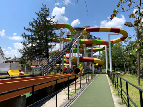 Colorful water slides twist and turn at a water park under a bright blue sky with a few clouds.