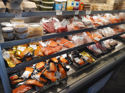 A display case filled with various types of fish and seafood, including salmon, tuna, and packaged items.
