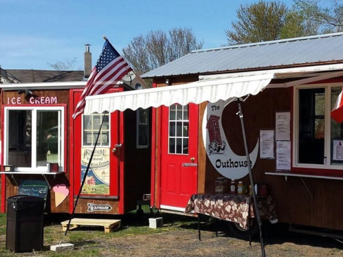 A colorful food truck area featuring an ice cream stand and a red building with an awning and an American flag.
