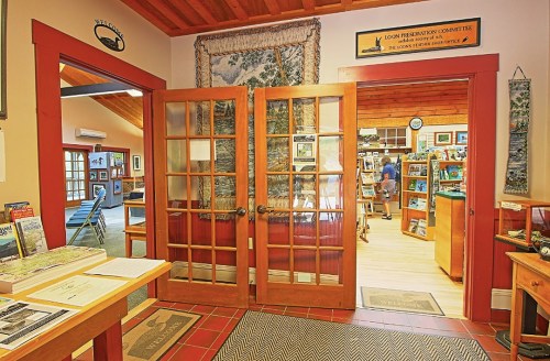 Interior view of a welcoming space with wooden double doors, showcasing a nature-themed display and a cozy shop area.
