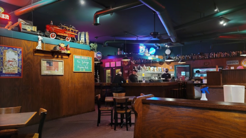 Cozy restaurant interior with wooden decor, vintage memorabilia, and patrons at the bar and dining area.
