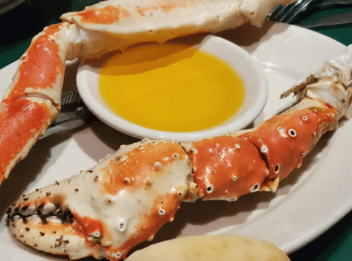 A plate with a large crab claw and a small bowl of melted butter for dipping.