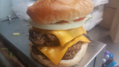 A stacked cheeseburger with two beef patties, melted cheese, lettuce, tomato, and onion on a toasted bun.