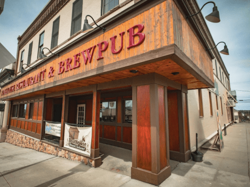 Exterior of a restaurant and brewpub with wooden accents and a prominent sign, located on a city street.