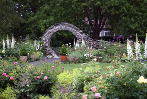 A stone archway surrounded by vibrant flowers and lush greenery in a serene garden setting.
