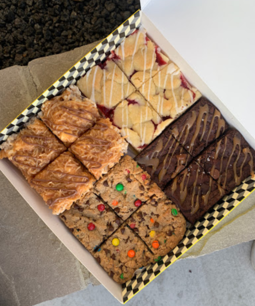 A box of assorted baked goods, including brownies, cookie bars, and fruit bars, neatly cut into squares.
