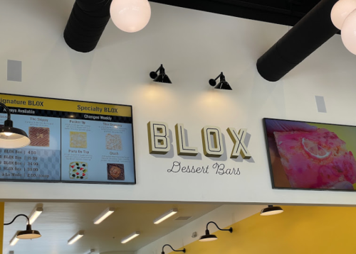 Signage for "BLOX Dessert Bars" with a menu display featuring various dessert options. Bright, modern interior.