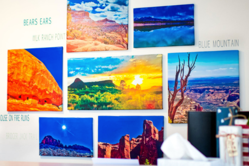 A wall display featuring colorful landscape photographs of various scenic locations, including Bears Ears and Blue Mountain.