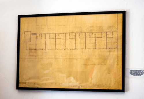 Blueprint of a building displayed in a black frame, featuring detailed architectural plans and measurements.
