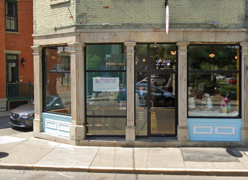 Exterior view of a corner storefront with large windows, featuring a sign for "Buttercup" and decorative columns.