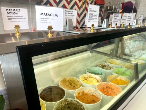 A display case filled with various ice cream flavors in cups, with menu signs above each flavor.