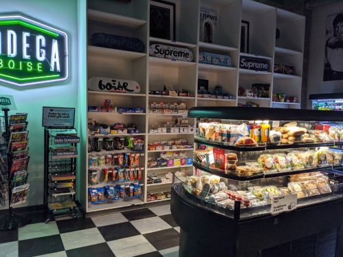A convenience store display with snacks, drinks, and a neon sign reading "Bodega Boise" in a modern setting.