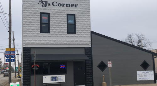 AJs Corner building with a sign, featuring a black and white exterior, located at a street intersection.