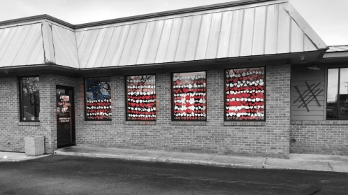 A building with windows decorated in red, white, and blue, resembling an American flag, against a gray sky.