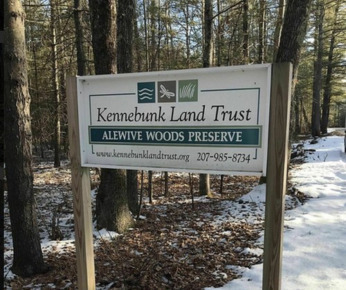 Sign for Kennebunk Land Trust's Alewive Woods Preserve, surrounded by trees and snow.