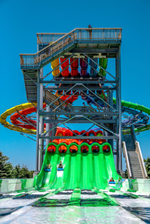 A colorful water slide structure with multiple slides and a tall tower under a clear blue sky.