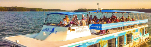 A scenic view of a boat filled with passengers cruising on a lake during sunset.