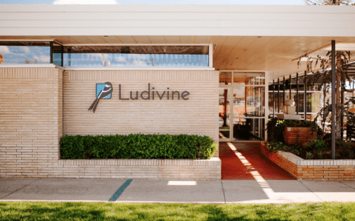 Exterior view of a modern building with a sign reading "Ludivine" and landscaped greenery in front.