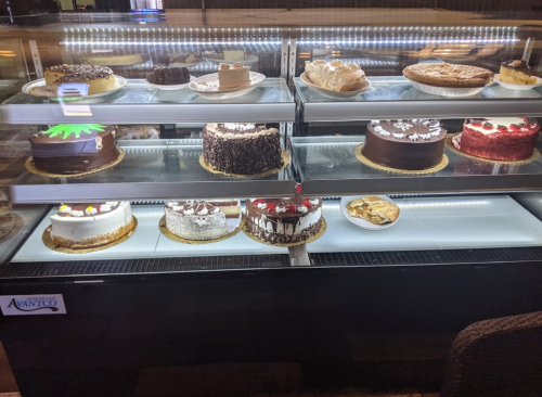 A display case filled with various cakes, including chocolate, fruit, and cream varieties, beautifully arranged.