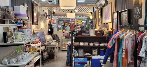 A vibrant indoor market stall filled with various vintage items, clothing, and decorative objects.