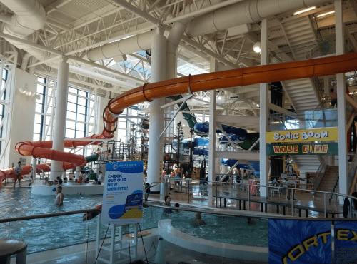 Indoor water park featuring colorful water slides, a wave pool, and visitors enjoying the attractions.