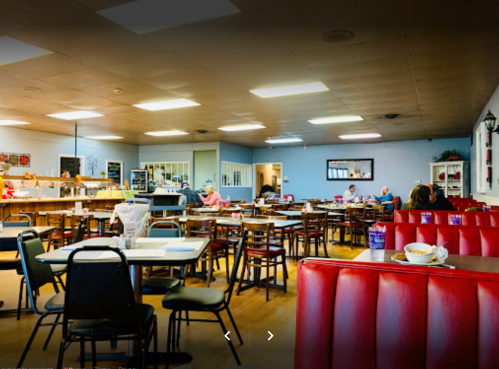 A cozy diner interior with red booths, wooden tables, and patrons enjoying meals in a bright, casual atmosphere.