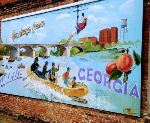 Mural depicting outdoor activities in Columbus, Georgia, featuring rafting, a zipline, and local landmarks.