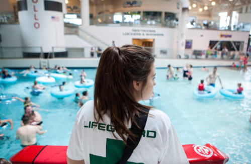 A lifeguard watches over a busy indoor pool filled with people in floaties.