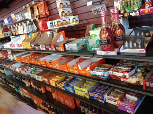 A colorful display of snacks and drinks on shelves, featuring candy bars, chips, and various beverages.