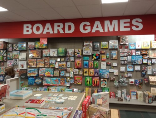 A display of various board games on shelves, with a prominent "BOARD GAMES" sign above.