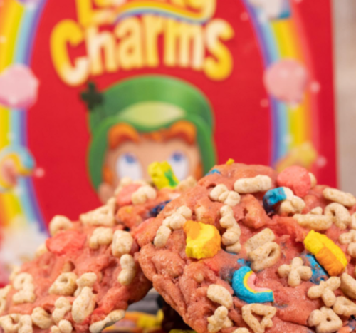 Colorful cookies topped with cereal, with a box of Lucky Charms in the background.