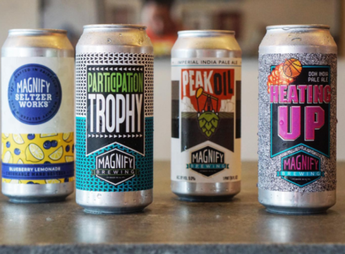 Four colorful beer cans from Magnify Brewing, featuring unique designs and flavors like blueberry lemonade and imperial IPA.