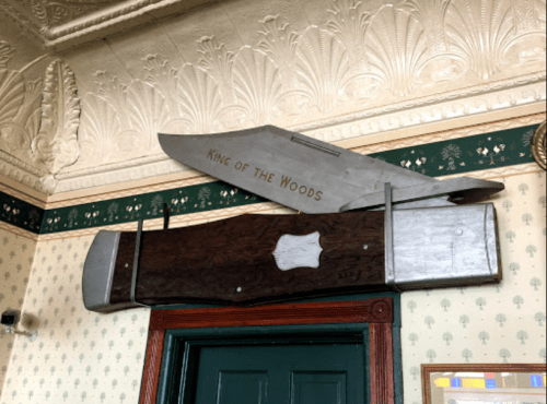 A large wooden and metal sign reading "King of the Woods" mounted above a door in a vintage interior.