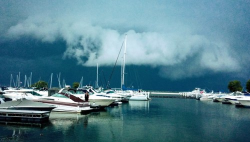 A marina filled with boats under a dark, stormy sky with ominous clouds.