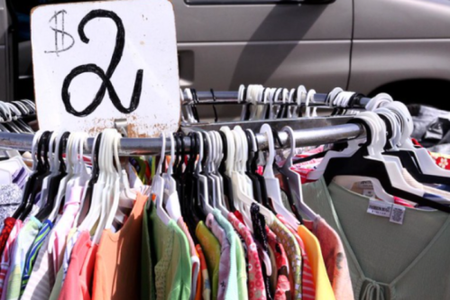 A clothing rack with various colorful garments, featuring a sign that reads "$2."