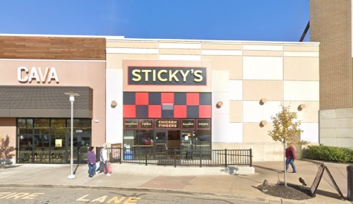 Exterior of Sticky's restaurant with a red and black sign, next to a Cava location, on a sunny day.