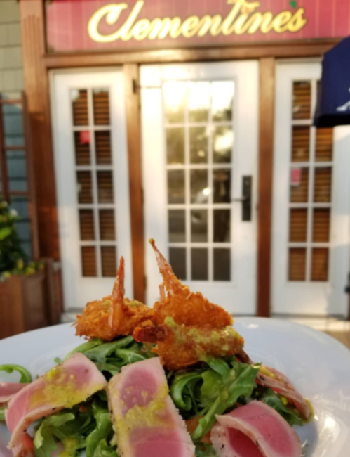 A vibrant salad with tuna and shrimp in front of a restaurant named Clementines.