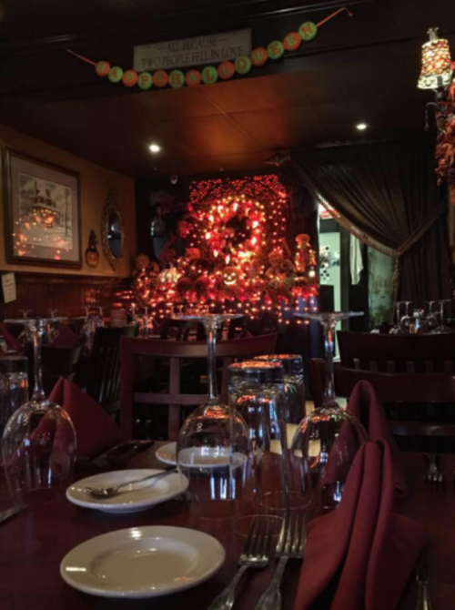 Cozy restaurant setting with elegantly set tables, glassware, and a festive, decorated backdrop.