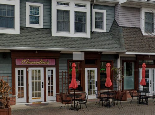 Exterior view of a restaurant named "Clementine's" with outdoor seating and red umbrellas on a brick-paved walkway.