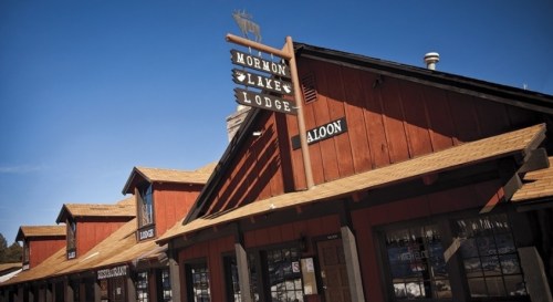 Sign for Mormon Lake Lodge and Saloon on a rustic wooden building under a clear blue sky.