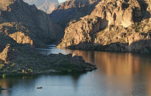 A serene lake surrounded by rocky hills, with a small boat on the water reflecting the evening light.