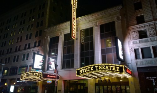 The illuminated facade of the State Theatre, featuring marquee lights and a vintage design, at night.