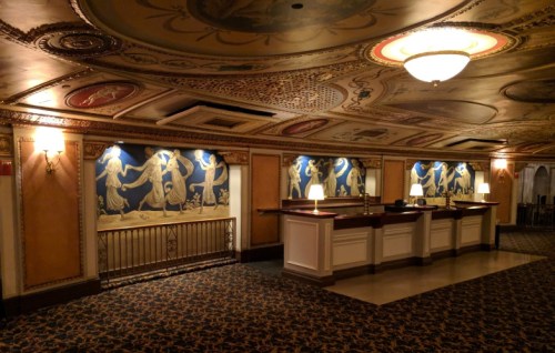 Elegant lobby with ornate ceiling, decorative wall murals, and a reception desk illuminated by soft lamps.