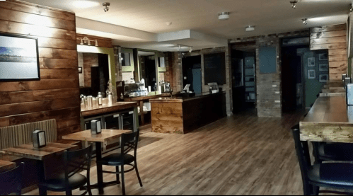 Cozy interior of a café with wooden walls, tables, and a counter, featuring warm lighting and a welcoming atmosphere.